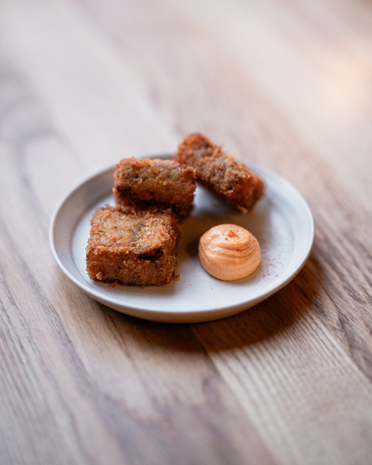 Photo of three croquettes and a dollop of mayonnaise, on a thick-rimmed plate.