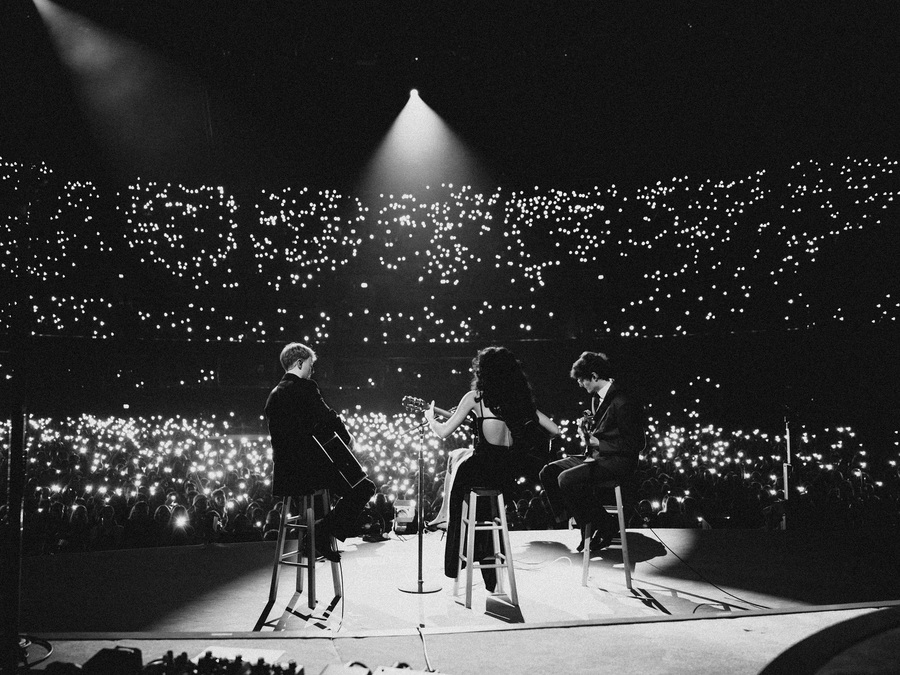 Black and white photo of Olivia Dean and two bandmates on stage at the OVO Hydro, Glasgow